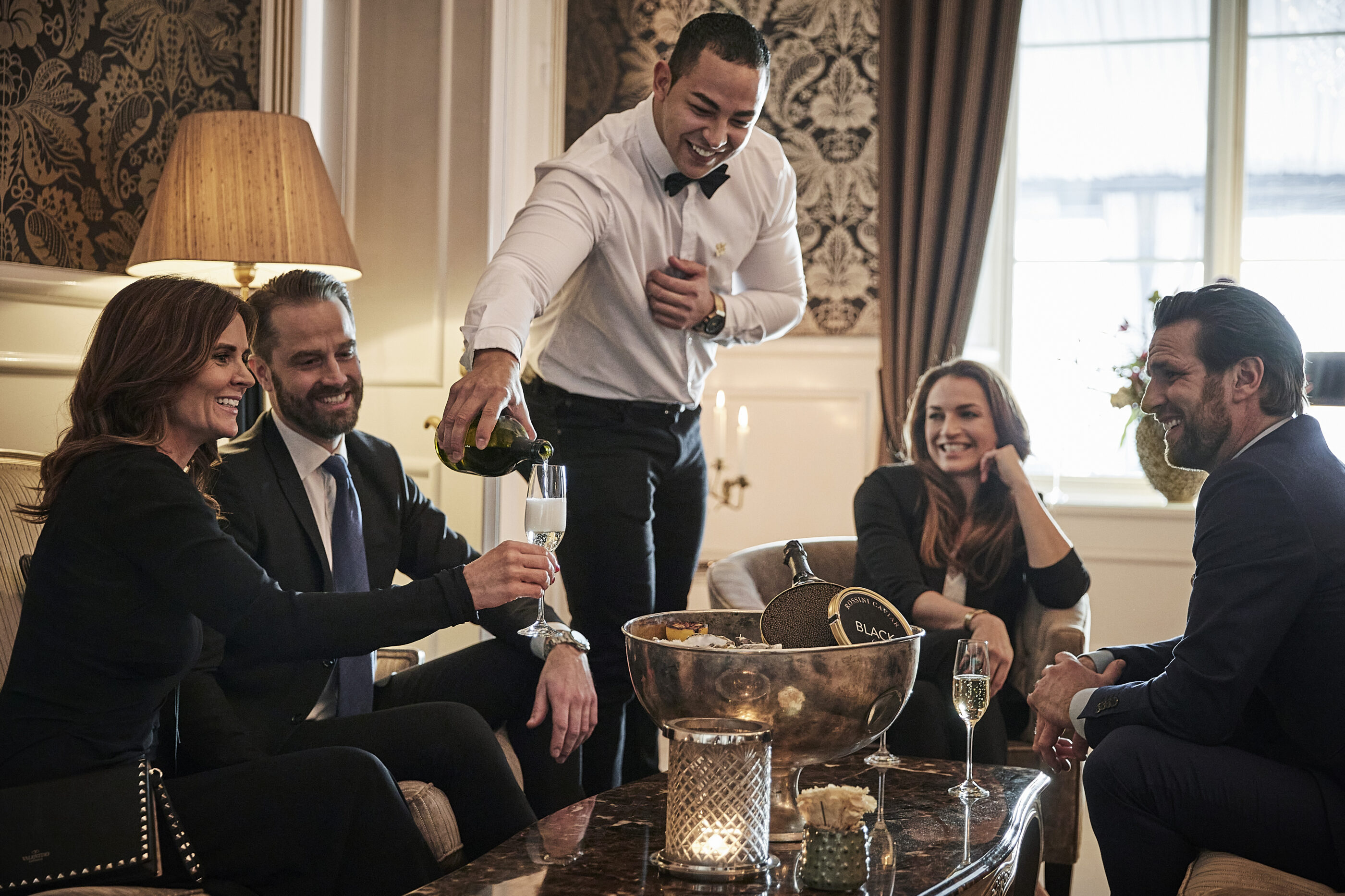 Waiter pouring champagne into glasses for guests